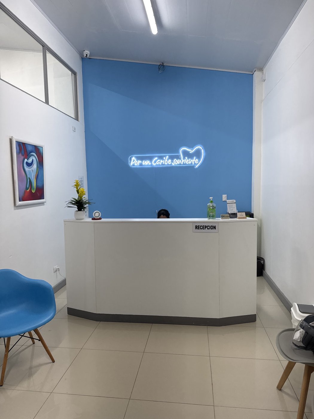 Recepción con la pared celeste y el neón «Por un Caribe sonriente»